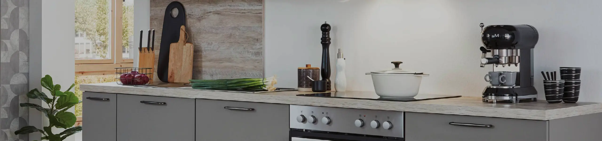 Helle Einbauküche mit Backofen, Kochfeld, Kaffeemaschine und Küchenaccessoires. Moderne Küchenzeile im zeitlosen Design für stilvolles Wohnen und Kochen.